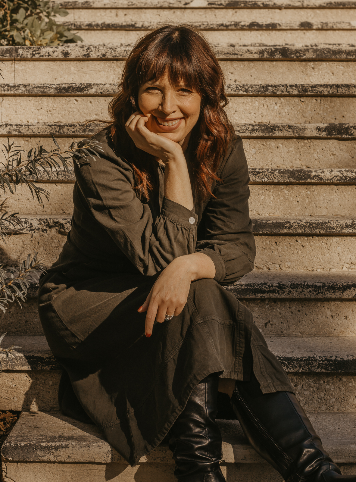Robin Joy sitting on sunlit stone steps, smiling