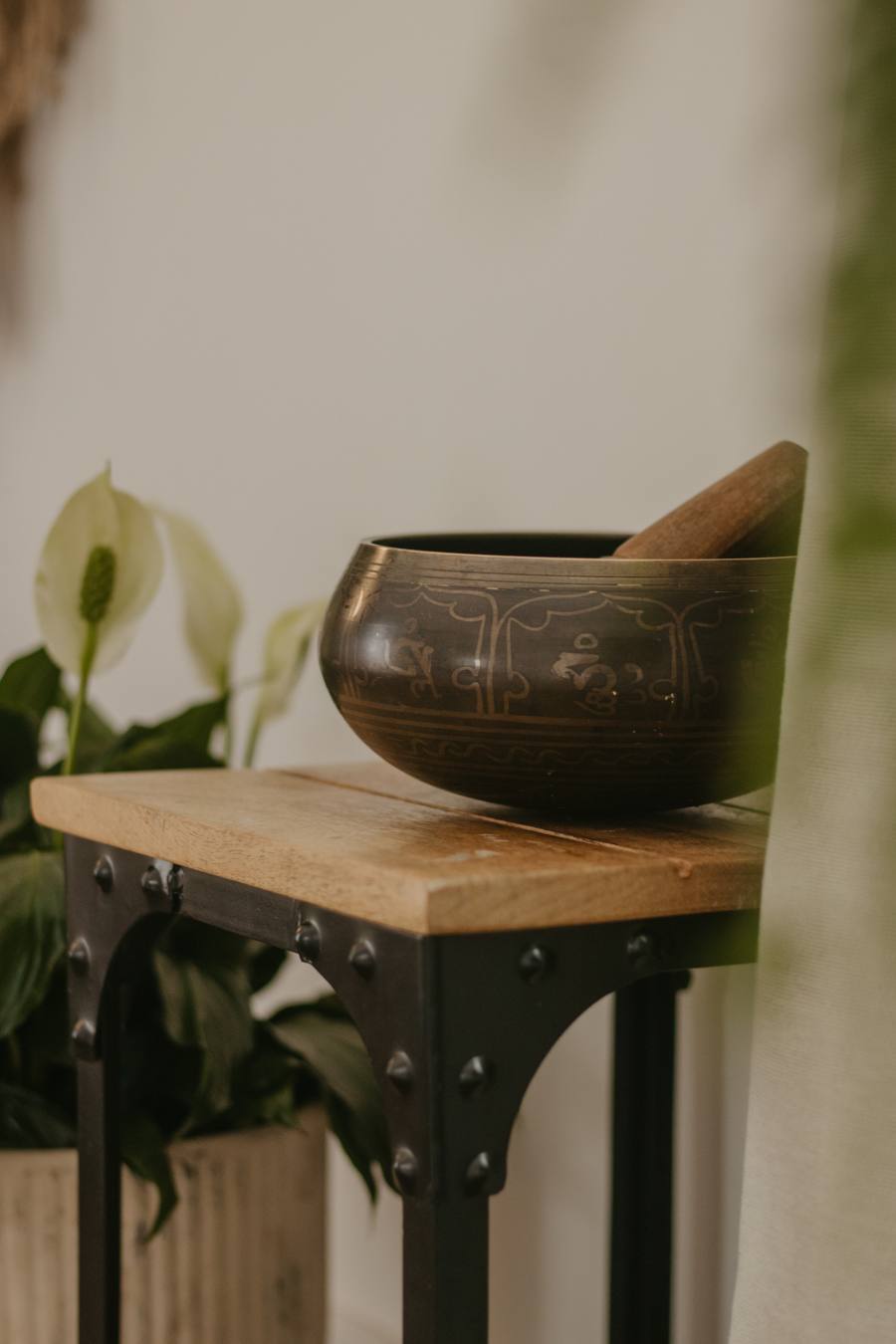 A singing bowl on a wooden table beside a plant